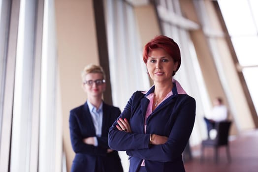 portrait  of two corporate business woman at modern bright office interior standing in group as team