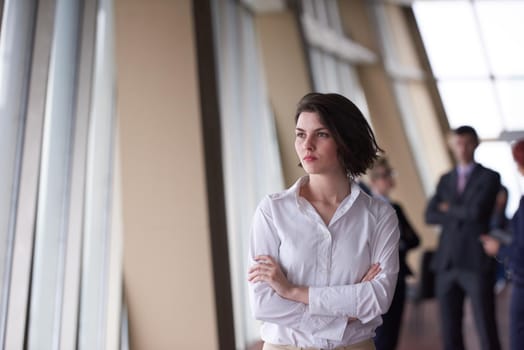 Smilling young business woman in front her team blured in background. Group of young business people. Modern bright  startup office interior.