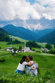 Santa Magdalena village in Val di Funes on the italian Dolomites. Autumnal view of the valley with colorful trees and Odle mountain group. Italy, man and woman on vacation, hiking in the mountains