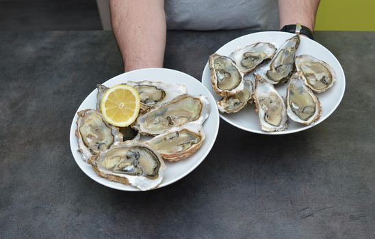 Man hands with lemon and oyster on a black background