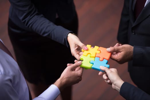 diverse business people group assembling jigsaw puzzle and represent team support and help concept, top view perspective at modern bright office interior