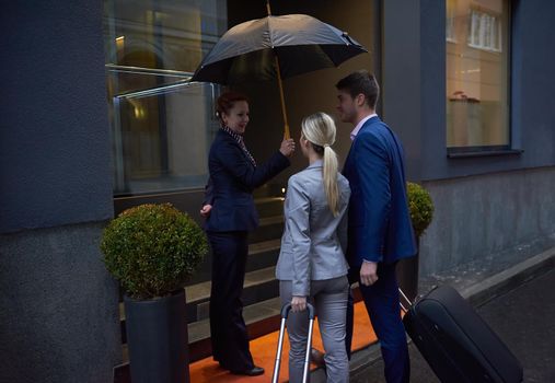 Young business people couple entering city  hotel, looking for room, holding suitcases while walking on street