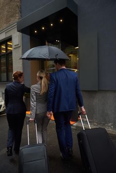 Young business people couple entering city  hotel, looking for room, holding suitcases while walking on street