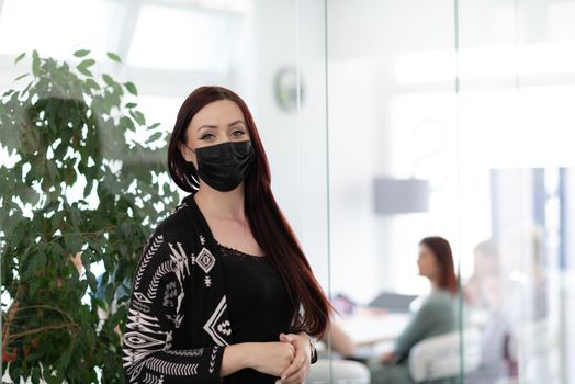 business woman portrait wearing medical mask in bright modern office new normal coronavirus outbreak concept real people