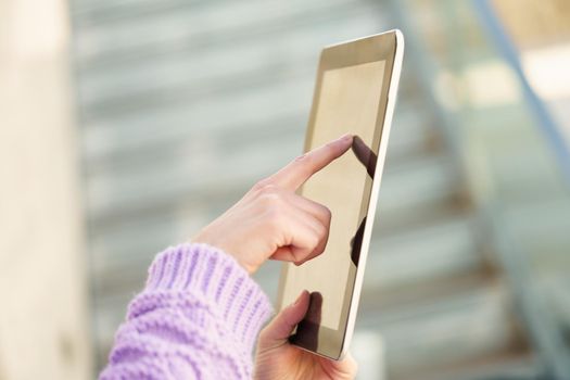 Detail of unrecognizable woman using digital tablet outdoors. Lifestyle concept.