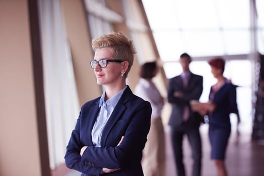 Smilling young business woman in front her team blured in background. Group of young business people. Modern bright  startup office interior.