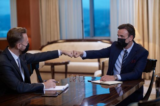 corporate business people on meeting in luxury office  wearing crona virus protection face mask keep social distance and handshake