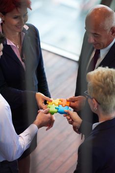 business people group assembling jigsaw puzzle and represent team support and help concept, top view perspective at modern bright office interior