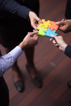 diverse business people group assembling jigsaw puzzle and represent team support and help concept, top view perspective at modern bright office interior