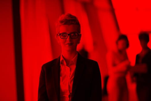 Smilling young business woman in front her team blured in background. Group of young business people. Modern bright  startup office interior.