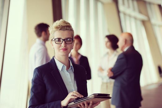 Smilling senior older  business woman with tablet computer  in front her team blured in background. Group of young business people at modern bright  startup office interior.