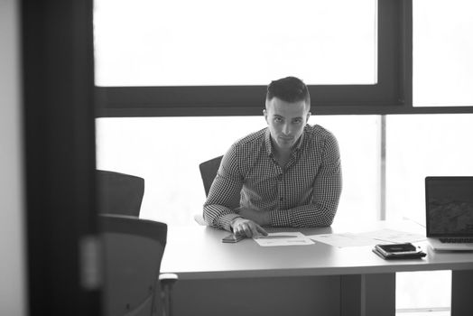 happy young businessman at his desk at work in modern startup business office interior