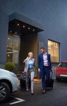 Young business people couple entering city  hotel, looking for room, holding suitcases while walking on street