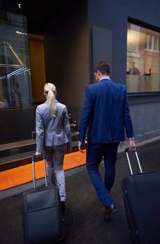 Young business people couple entering city  hotel, looking for room, holding suitcases while walking on street