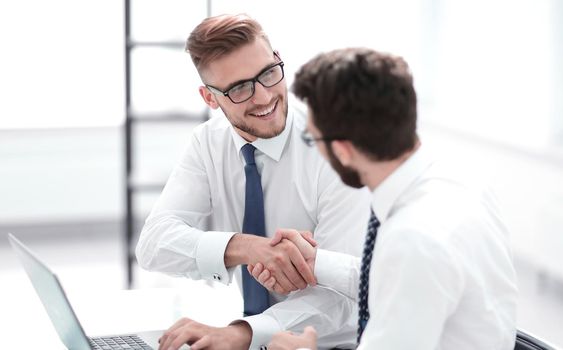 side view.smiling employees shaking hands .photo with copy space