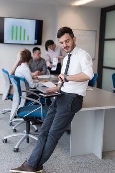 Portrait of happy young businessman with tablet computer office. People group on team meeting in background