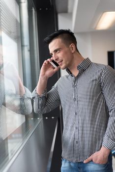 relaxed young businessman speaking on smart phone at modern startup business office meeting room  with big window and city in backgronud