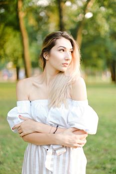 Young blonde european woman standing in garden. Concept of summer fashion and walking in park.