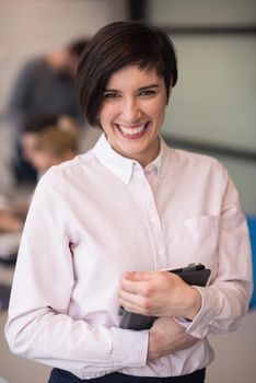 young hispanic businesswoman portrait with  tablet computer at modern startup business office interior, people group on team meeting blured in background