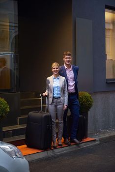 Young business people couple entering city  hotel, looking for room, holding suitcases while walking on street