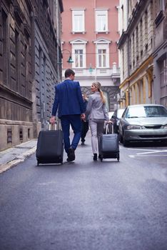 Young business people couple entering city  hotel, looking for room, holding suitcases while walking on street