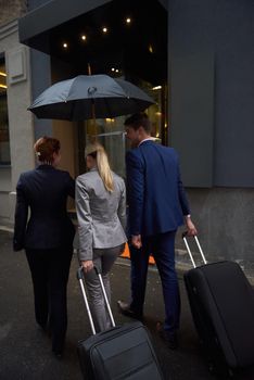 Young business people couple entering city  hotel, looking for room, holding suitcases while walking on street