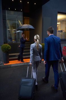 Young business people couple entering city  hotel, looking for room, holding suitcases while walking on street