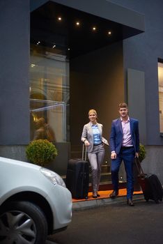 Young business people couple entering city  hotel, looking for room, holding suitcases while walking on street