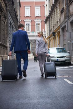 Young business people couple entering city  hotel, looking for room, holding suitcases while walking on street