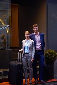 Young business people couple entering city  hotel, looking for room, holding suitcases while walking on street