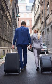 Young business people couple entering city  hotel, looking for room, holding suitcases while walking on street