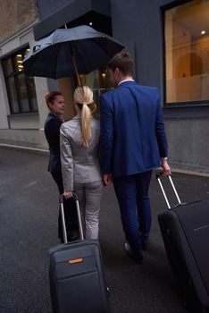 Young business people couple entering city  hotel, looking for room, holding suitcases while walking on street