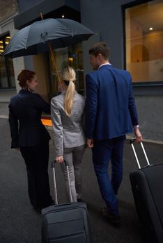 Young business people couple entering city  hotel, looking for room, holding suitcases while walking on street