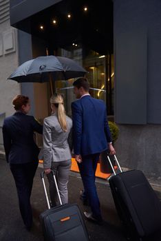 Young business people couple entering city  hotel, looking for room, holding suitcases while walking on street