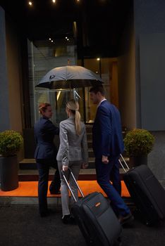 Young business people couple entering city  hotel, looking for room, holding suitcases while walking on street