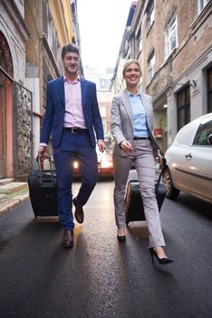 Young business people couple entering city  hotel, looking for room, holding suitcases while walking on street