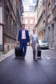 Young business people couple entering city  hotel, looking for room, holding suitcases while walking on street