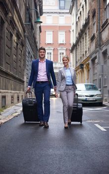 Young business people couple entering city  hotel, looking for room, holding suitcases while walking on street