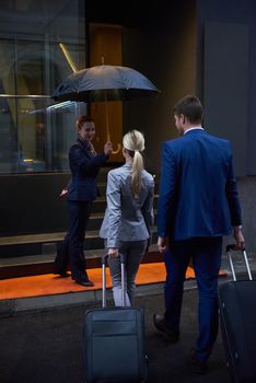 Young business people couple entering city  hotel, looking for room, holding suitcases while walking on street