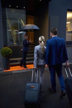 Young business people couple entering city  hotel, looking for room, holding suitcases while walking on street