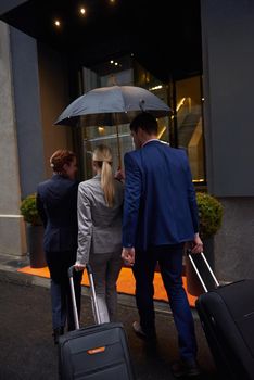 Young business people couple entering city  hotel, looking for room, holding suitcases while walking on street