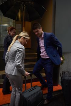 Young business people couple entering city  hotel, looking for room, holding suitcases while walking on street