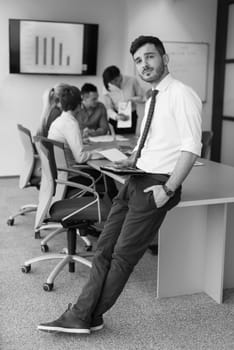 Portrait of happy young businessman with tablet computer office. People group on team meeting in background