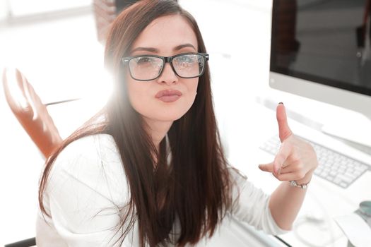 business woman shows a thumb up, sitting at the Desk. success concept