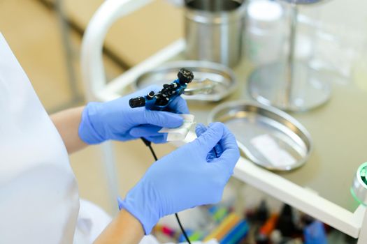 Closeup cosmetologist hands in latex gloves inserting needle into microblading device at beauty salon. Concept of cosmetology equipment for permanent makeup.