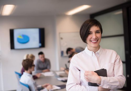 young hispanic businesswoman portrait with  tablet computer at modern startup business office interior, people group on team meeting blured in background