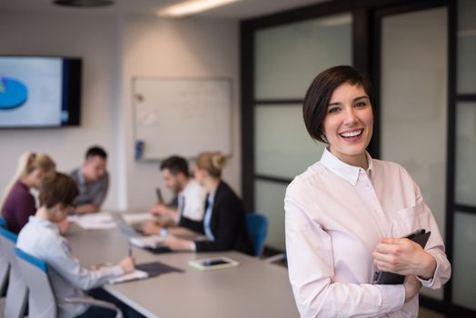 young hispanic businesswoman portrait with  tablet computer at modern startup business office interior, people group on team meeting blured in background