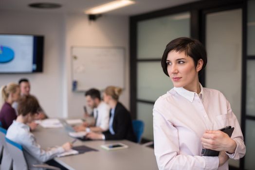 young hispanic businesswoman portrait with  tablet computer at modern startup business office interior, people group on team meeting blured in background