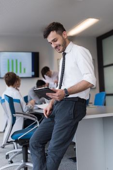 Portrait of happy young businessman with tablet computer office. People group on team meeting in background