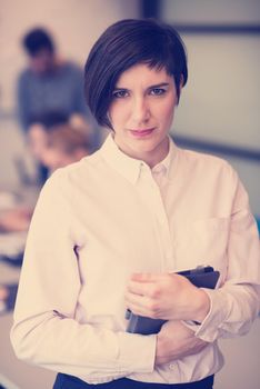 young hispanic businesswoman portrait with  tablet computer at modern startup business office interior, people group on team meeting blured in background